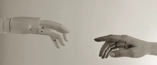 Roboterhand und menschliche Hand – KI und Mensch arbeiten zusammen