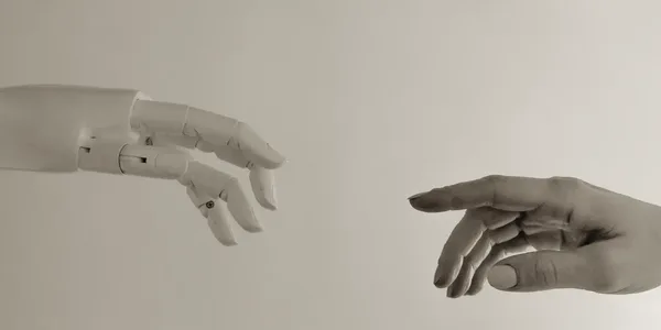 Roboterhand und menschliche Hand – KI und Mensch arbeiten zusammen